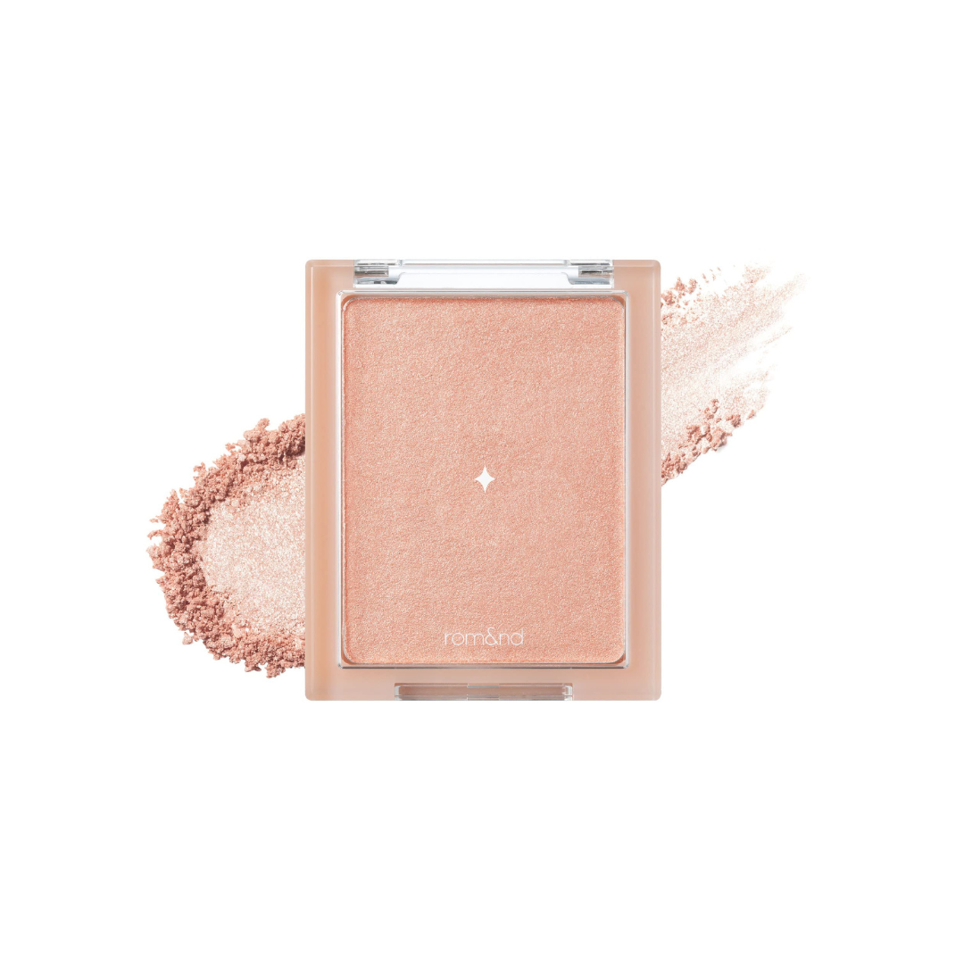 Kompakt med ferskenfarvet highlighter og spredt pudder, viser produktets tekstur og farve.