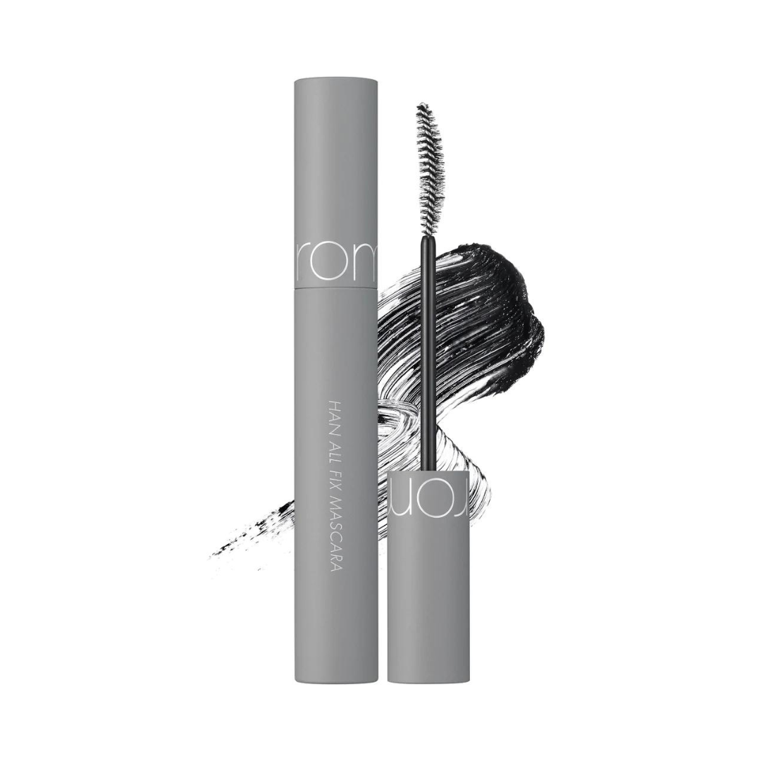 Grå mascara med sort børste og penselstrøg baggrund, produktnavn på tube: Han All Fix Mascara.