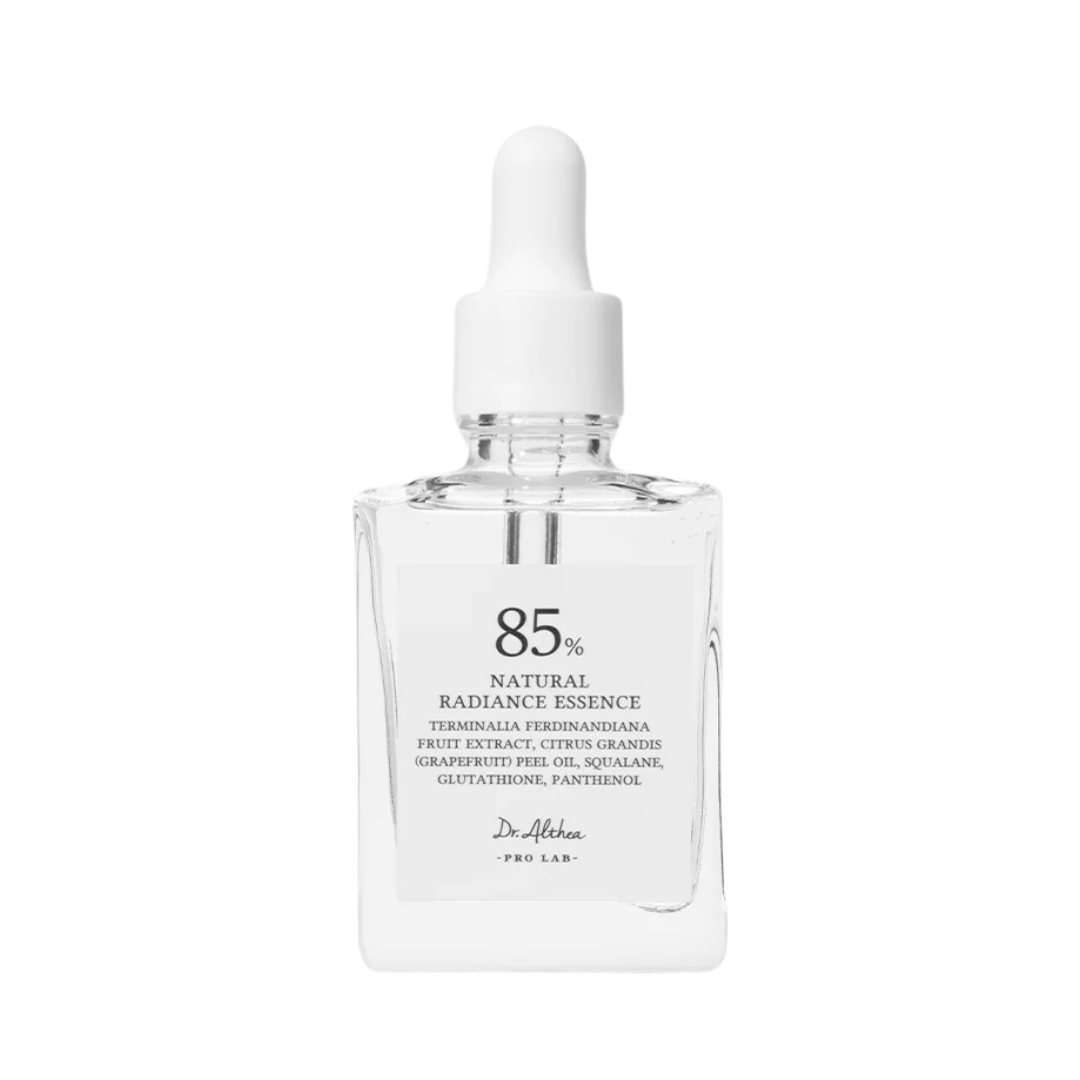 Klar glasflaske med hvid dråbehætte, mærket med "85% Natural Radiance Essence" og ingredienser.