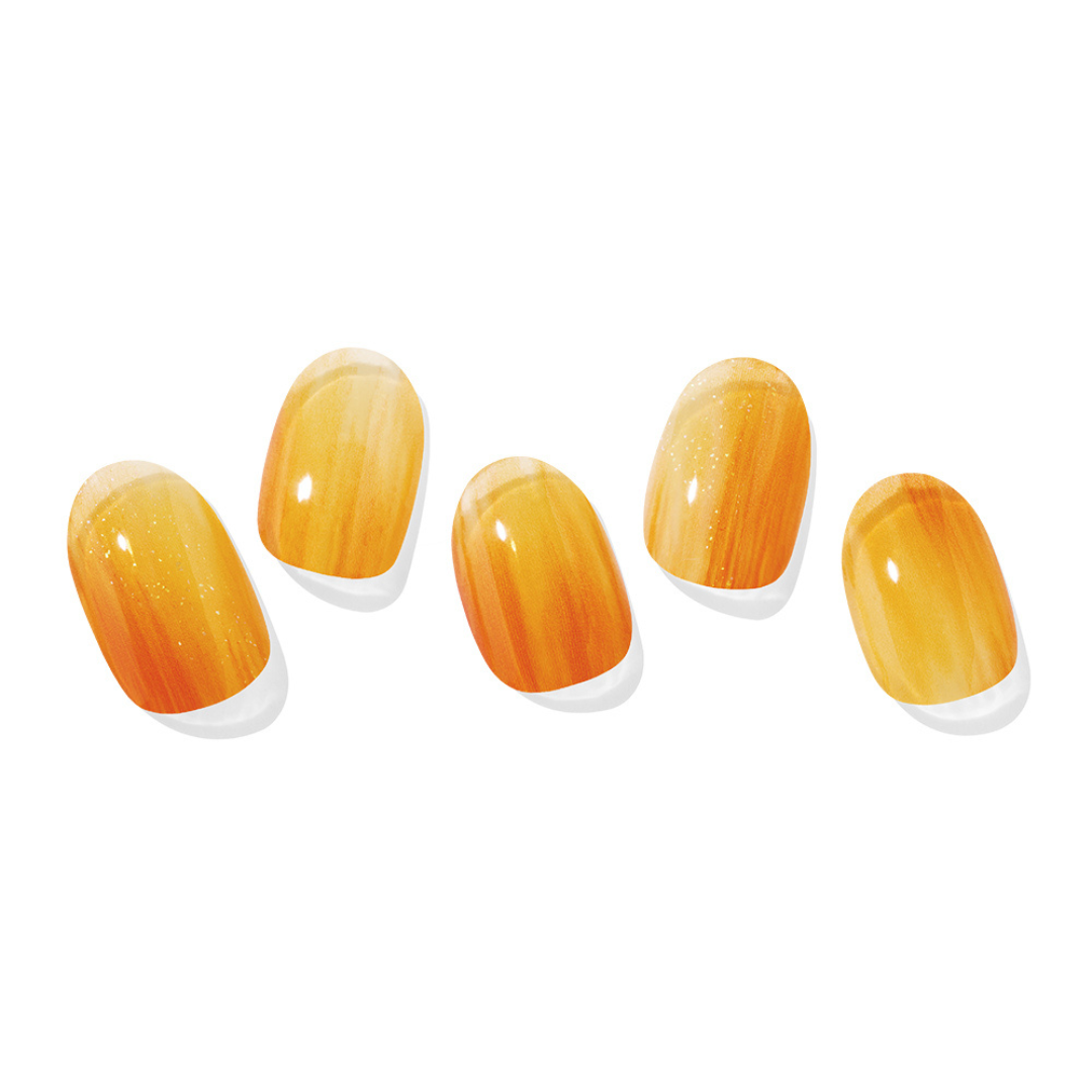 Fem kunstige negle med skinnende orange marmeladegradient og diskrete glitrende detaljer.