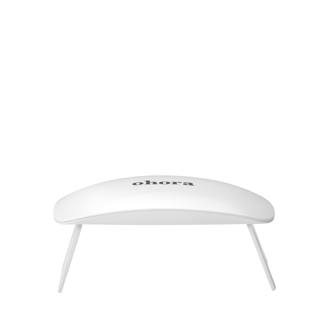 Hvid, kurvet Ohora gel-lampe med sort logo på toppen, stående på to ben.