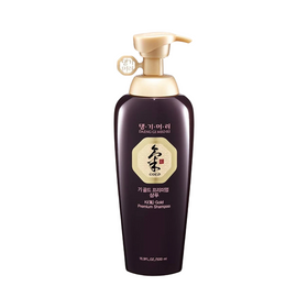 Mørk flaske med pumpe, mærket "Daeng Gi Meo Ri Ki Gold Premium Shampoo" i guld og sort tekst.