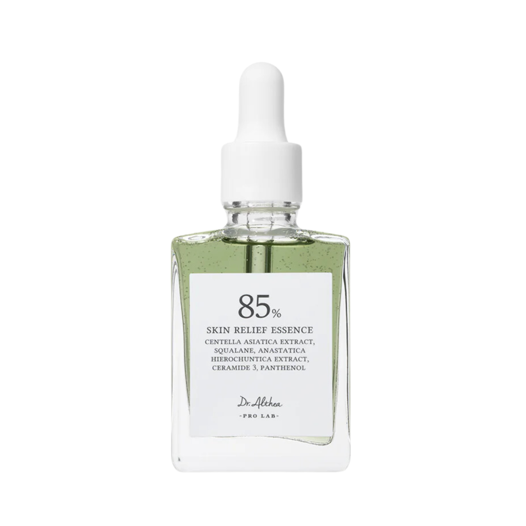 Klar flaske med grøn væske, hvid dråbehætte. Etiket: "85% Skin Relief Essence" med ingredienser.