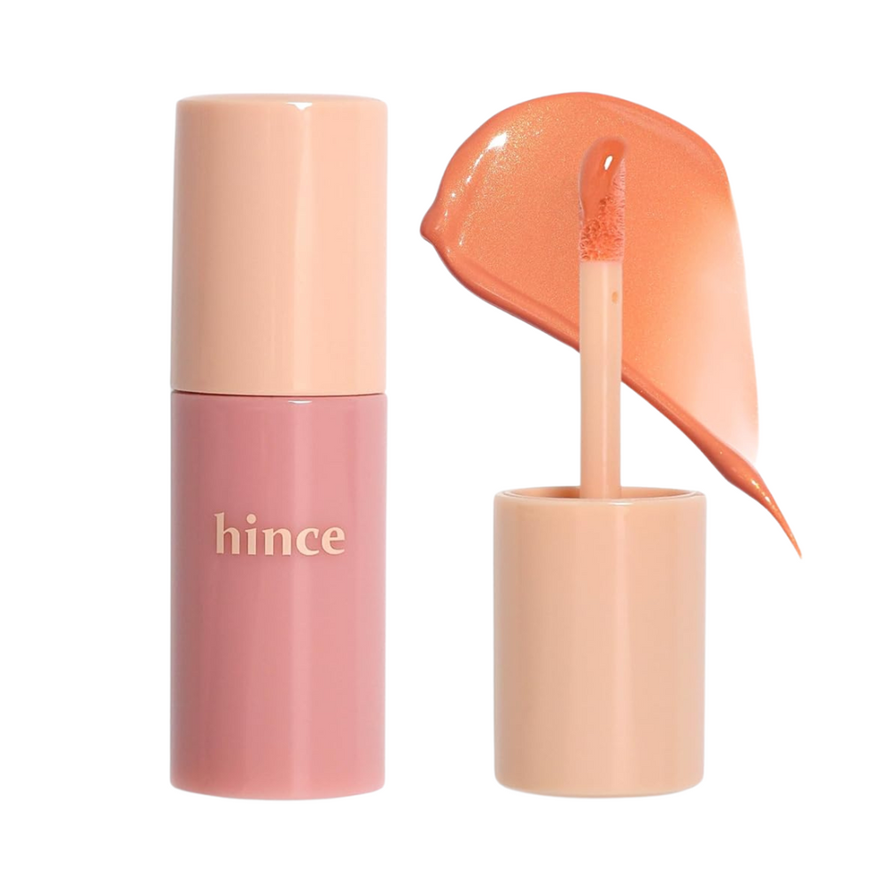 Hince flydende blush i en lyserød beholder, med applikator og varm orange nuance påført.