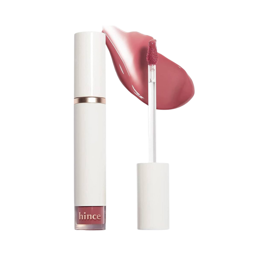 Hvid tube med rosaguld bånd, lipgloss applikator og pink glansprøve fra Hince.