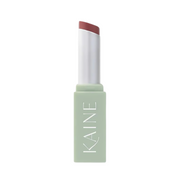 Pastelgrøn tube med "KAINE", indeholder en rosa blommefarvet lip balm.