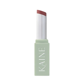 Pastelgrøn tube med "KAINE", indeholder en rosa blommefarvet lip balm.