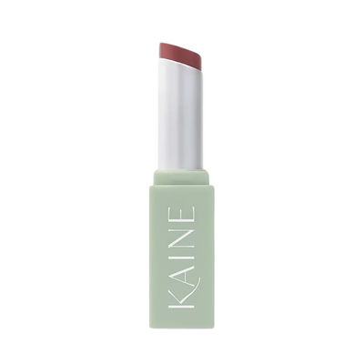 Pastelgrøn tube med "KAINE", indeholder en rosa blommefarvet lip balm.