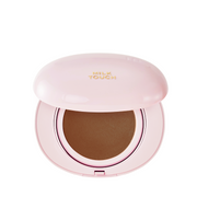 Lys rosa kompakt med brun cushion, åbnet, "Milk Touch" står på låget.