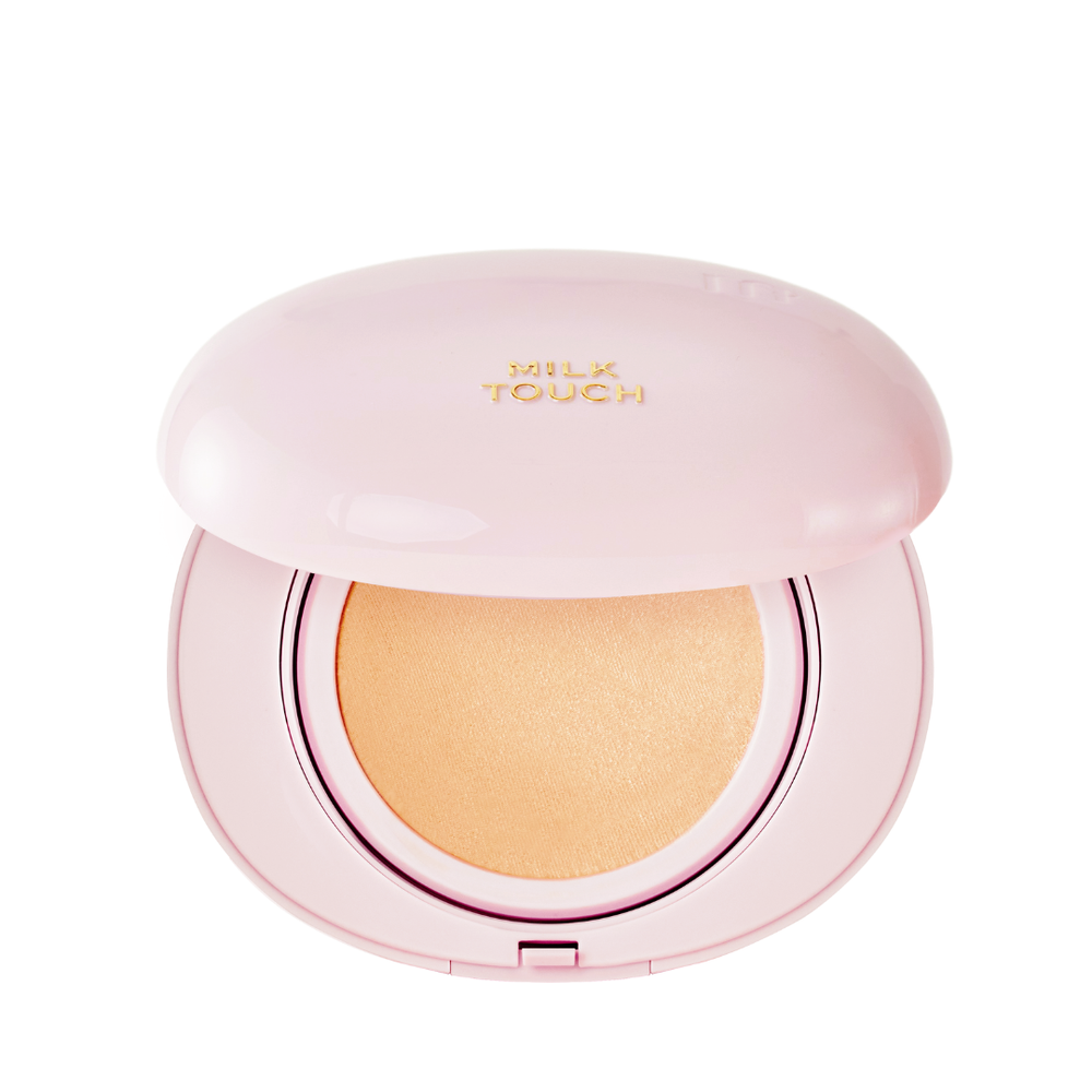 Lys pink kompakt med beige pudder, let åbnet. "Milk Touch" står med guldbogstaver på låget.