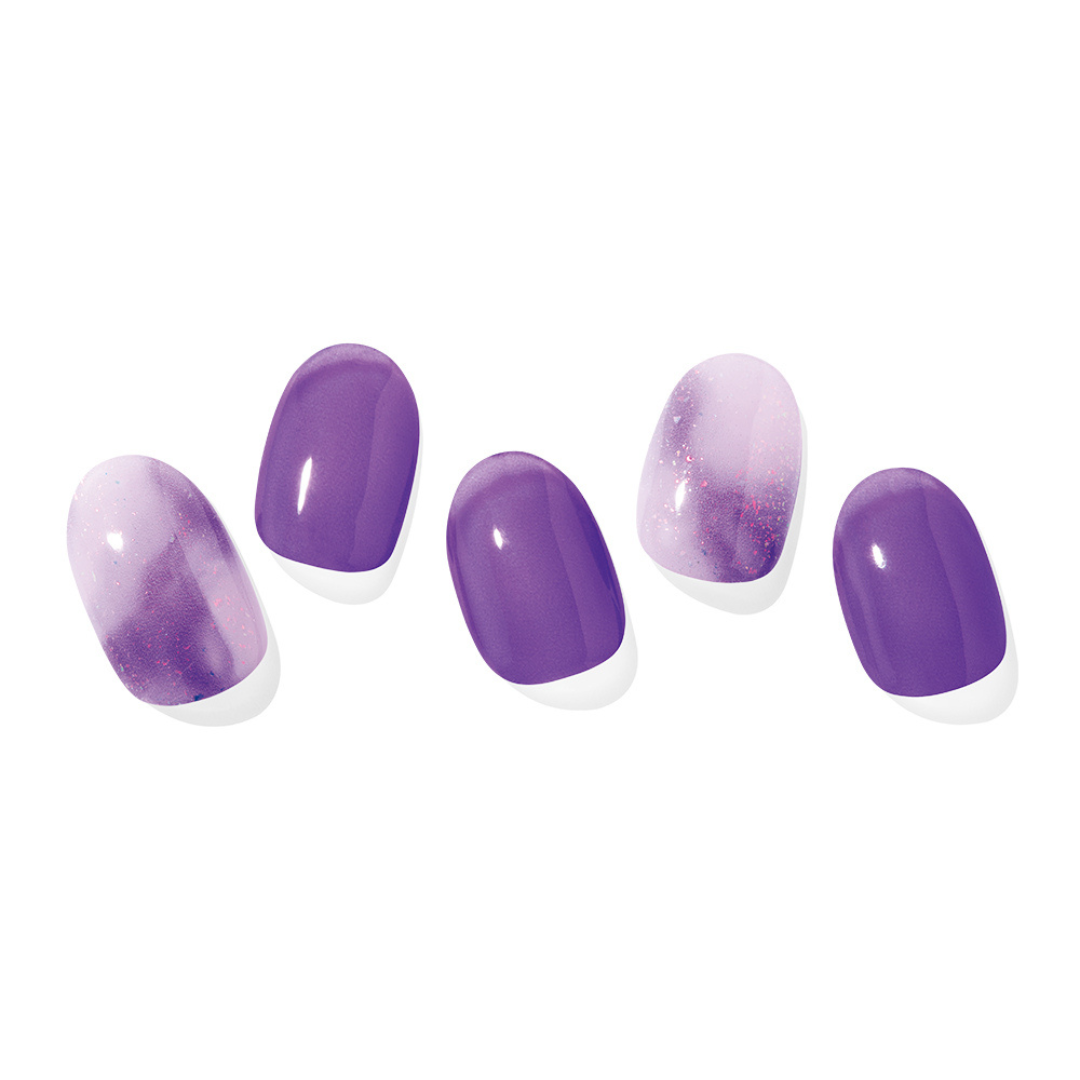 Fem falske negle, tre lilla og to med lilla til lys gradient og glimmer.