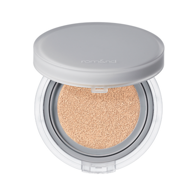 Grå kompaktpude med beige makeup indeni, åben, mærket "rom&nd" på låget.