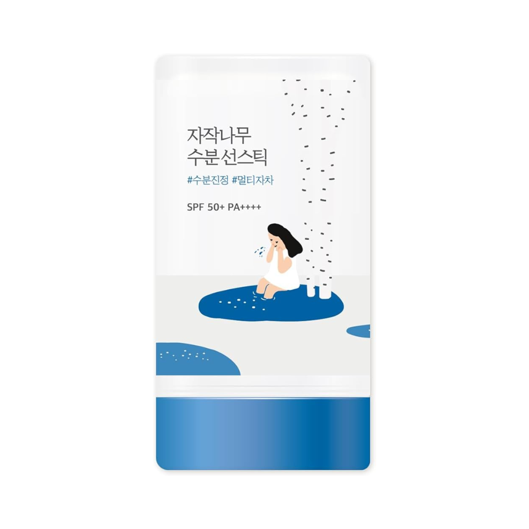 Produktpakke med koreansk tekst, kvinde ved birketræer, SPF 50+ PA++++ angivet.