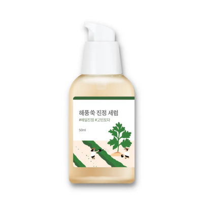 Flaske med Round Lab Mugwort Calming Serum, grøn plante og koreansk tekst på etiketten.