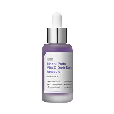 Flaske med sølvhætte, lilla væske, label "Meoru Podo Vita C Dark Spot Ampoule," ingredienser opført.