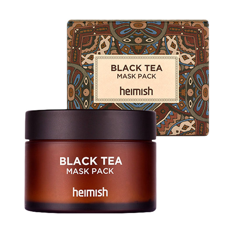 Brun krukke med sort låg, mærket "Black Tea Mask Pack", foran mønstret æske.