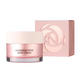 Lyserød krukke med hvidt låg, mærket "Bulgarian Rose Satin Cream", ved siden af matchende æske med rosedesign.